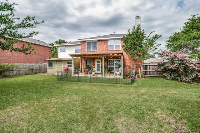 rear view of property with a yard, brick siding, a patio area, and a fenced backyard