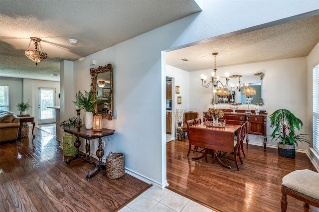 dining space featuring a textured ceiling, an inviting chandelier, wood finished floors, and baseboards