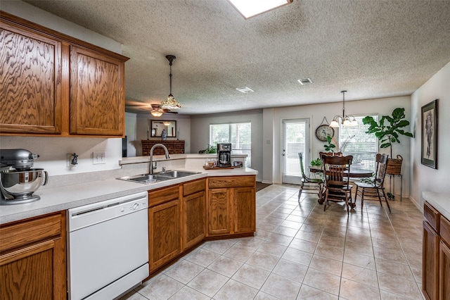 kitchen featuring light countertops, dishwasher, decorative light fixtures, and a sink