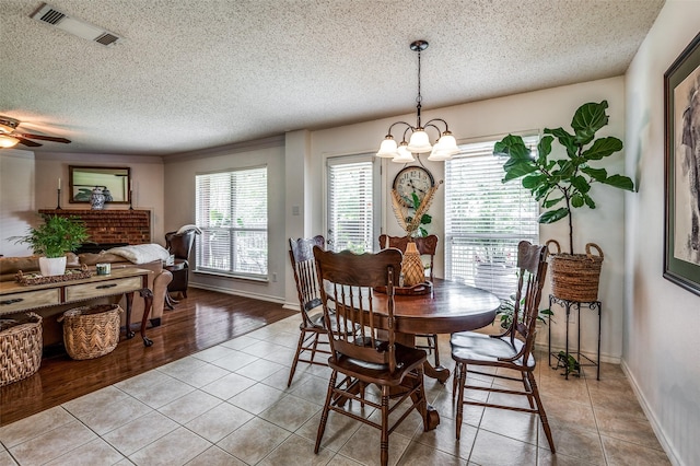 dining room featuring light tile patterned floors, visible vents, a textured ceiling, and ceiling fan with notable chandelier