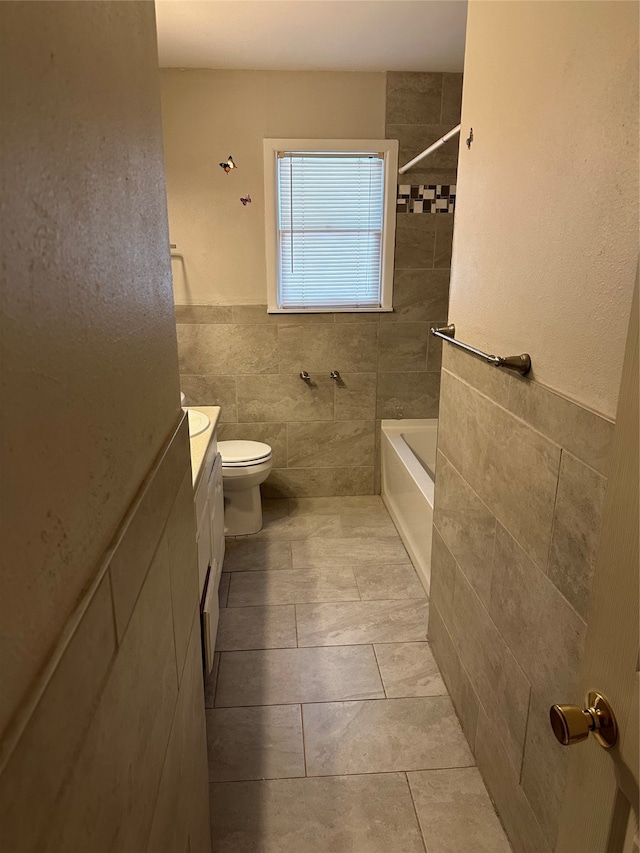 full bathroom featuring tile walls, tiled shower / bath, tile floors, toilet, and vanity