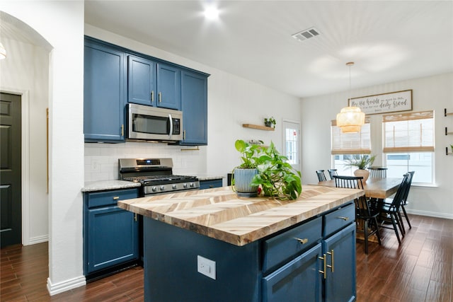 kitchen with blue cabinetry, dark wood-type flooring, backsplash, wood counters, and appliances with stainless steel finishes