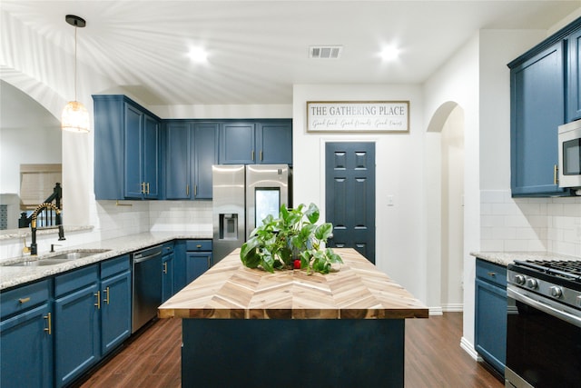 kitchen featuring appliances with stainless steel finishes, a center island, tasteful backsplash, and butcher block counters