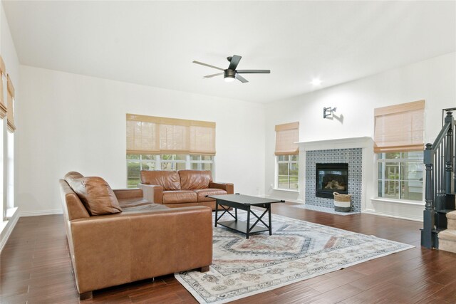 living room featuring dark hardwood / wood-style flooring, a tiled fireplace, and ceiling fan