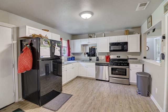 kitchen featuring sink, light hardwood / wood-style flooring, white cabinets, and black appliances