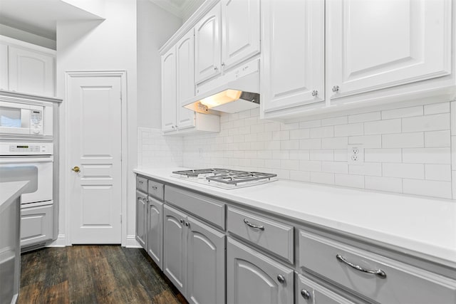 kitchen featuring white cabinetry, dark wood-type flooring, gray cabinetry, white appliances, and tasteful backsplash