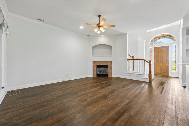 unfurnished living room featuring ceiling fan, a tiled fireplace, crown molding, and dark wood-type flooring