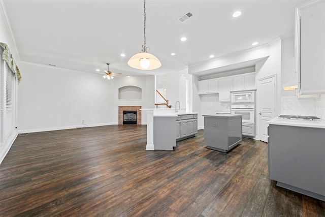 kitchen featuring a center island, white appliances, dark hardwood / wood-style floors, and a tile fireplace