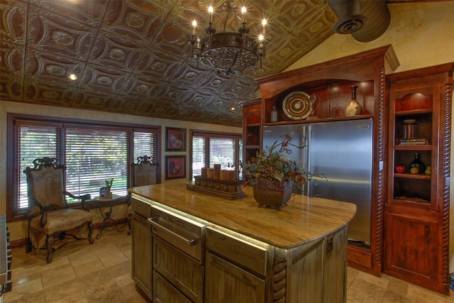 kitchen with a kitchen island, lofted ceiling, high end refrigerator, and light tile floors