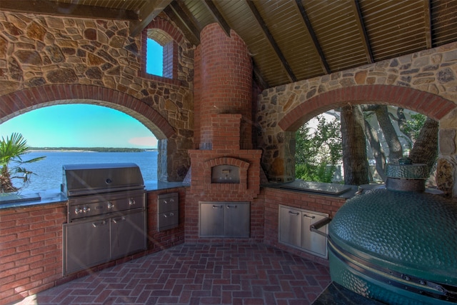 view of patio featuring exterior kitchen, a water view, and grilling area