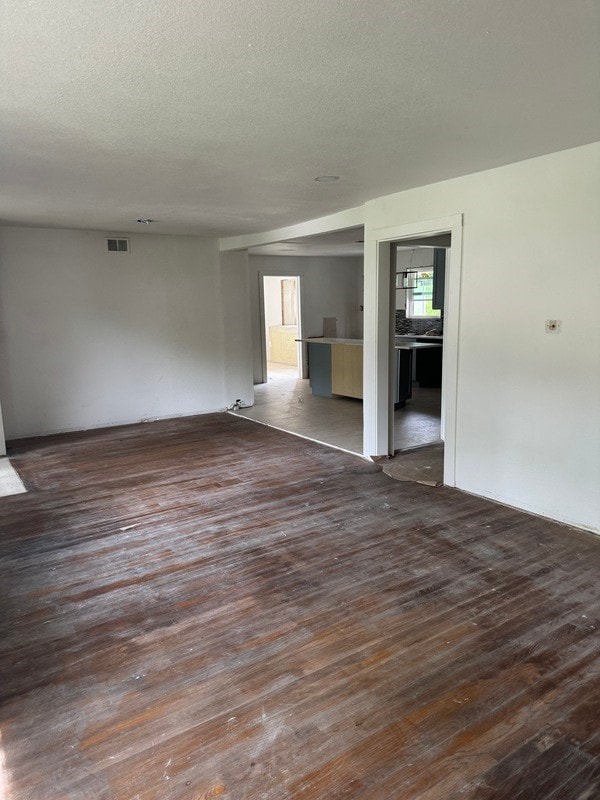 spare room with a healthy amount of sunlight, a textured ceiling, and dark hardwood / wood-style floors