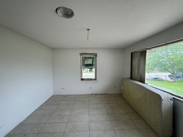 unfurnished room featuring a textured ceiling and light tile flooring