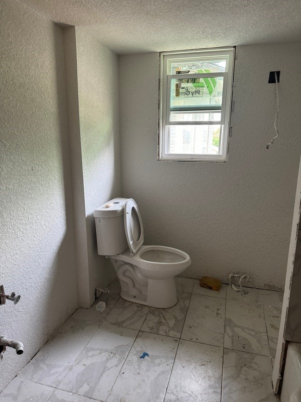 bathroom with tile floors, toilet, and a textured ceiling