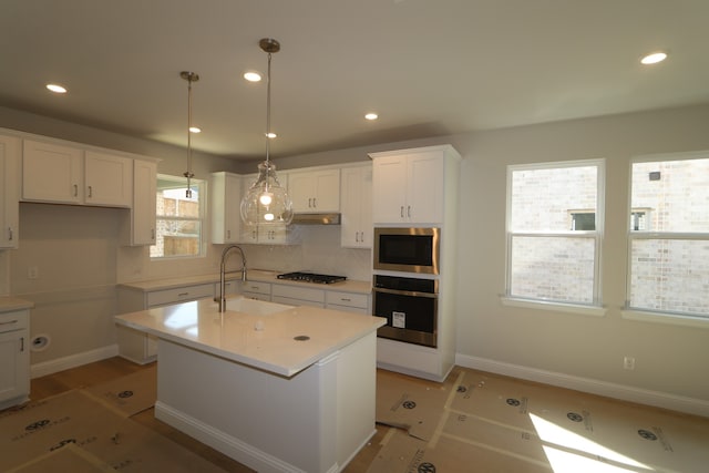 kitchen featuring a wealth of natural light, white cabinets, hanging light fixtures, and appliances with stainless steel finishes