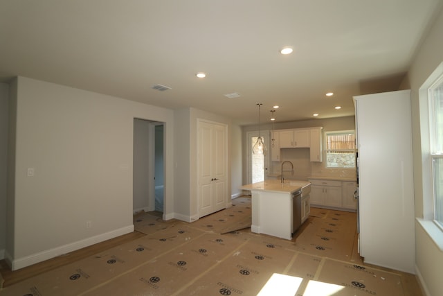 kitchen featuring pendant lighting, a center island with sink, decorative backsplash, light tile patterned floors, and white cabinetry