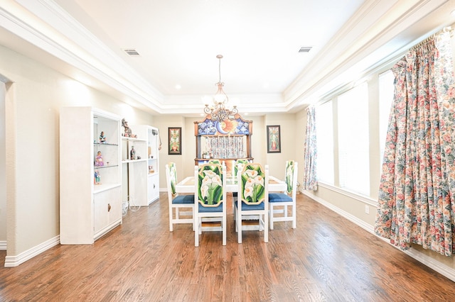 dining room featuring hardwood / wood-style flooring, a notable chandelier, crown molding, and a tray ceiling