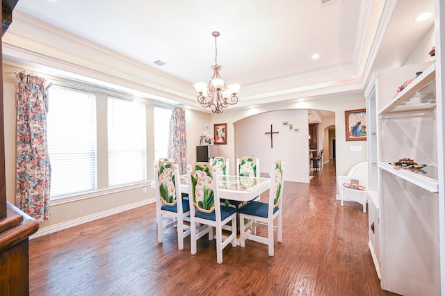 dining space featuring dark hardwood / wood-style flooring, a tray ceiling, an inviting chandelier, and crown molding