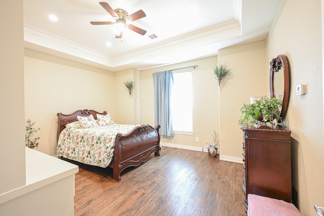 bedroom with ceiling fan, ornamental molding, dark wood-type flooring, and a tray ceiling