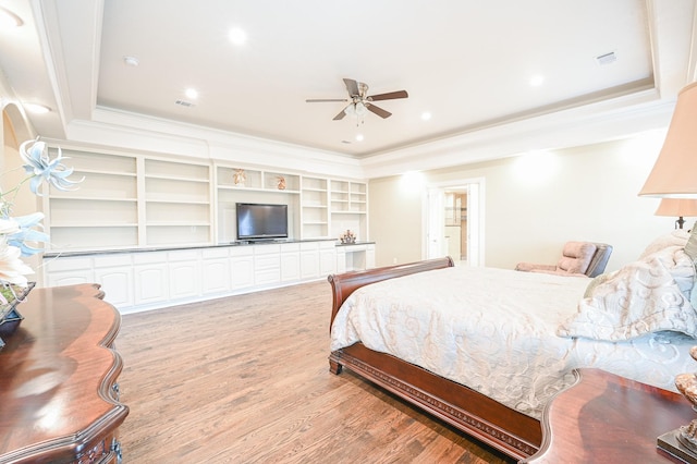 bedroom featuring ceiling fan, light hardwood / wood-style floors, a raised ceiling, and crown molding