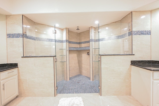 bathroom with vanity, walk in shower, and tile walls