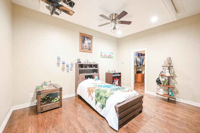 bedroom with hardwood / wood-style floors, a closet, a spacious closet, and ceiling fan