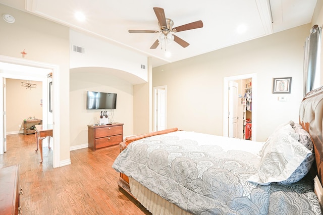 bedroom with ceiling fan, light wood-type flooring, a spacious closet, and a closet