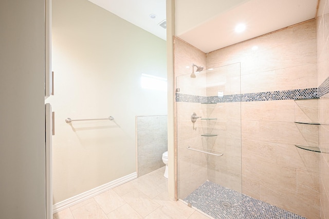 bathroom featuring a tile shower, toilet, and tile patterned floors