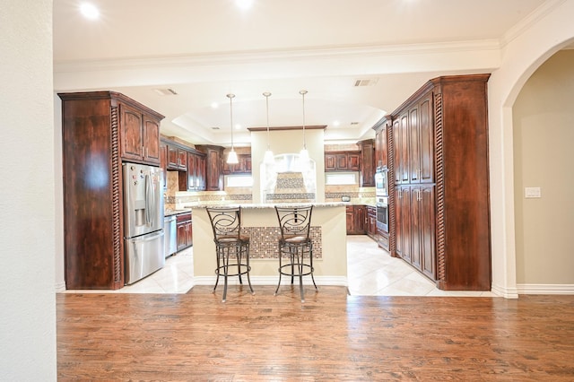 kitchen with appliances with stainless steel finishes, light stone counters, a breakfast bar, light hardwood / wood-style flooring, and a center island