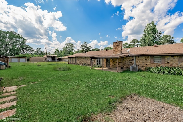 view of yard featuring a patio, an outdoor structure, central AC unit, and a garage