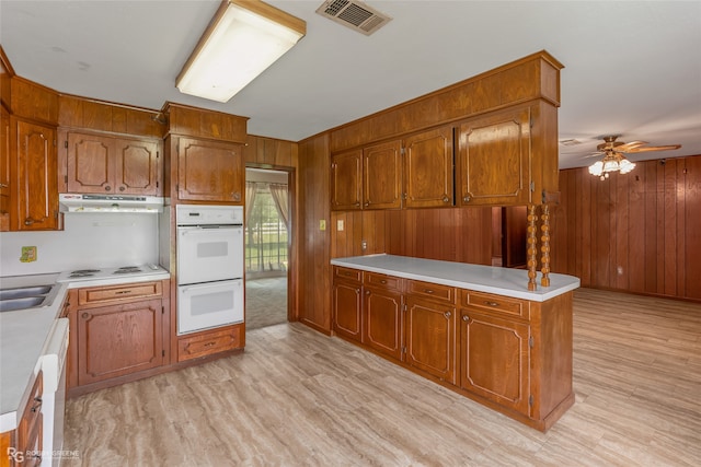 kitchen featuring ceiling fan, light hardwood / wood-style flooring, white appliances, exhaust hood, and wooden walls