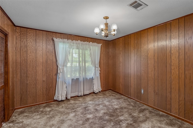 spare room with carpet, an inviting chandelier, and wood walls