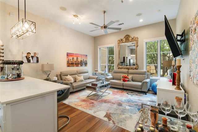 living room with wood-type flooring, ceiling fan with notable chandelier, and a wealth of natural light