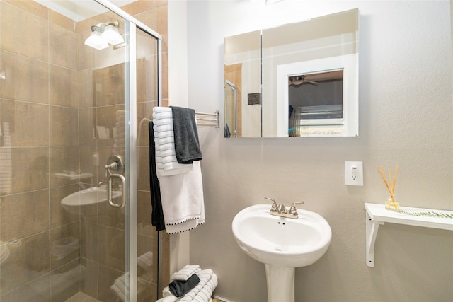 bathroom with a shower with shower door and sink