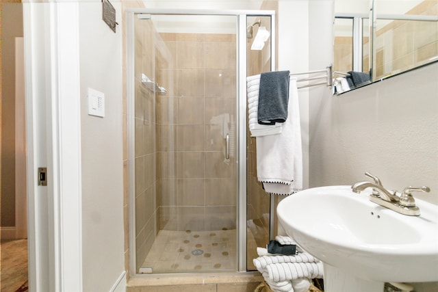 bathroom with an enclosed shower, sink, and tile patterned flooring