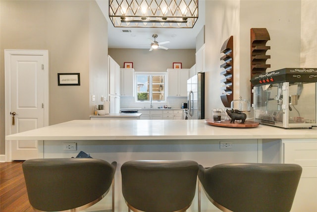 kitchen with sink, stainless steel fridge, dark hardwood / wood-style flooring, white cabinets, and ceiling fan