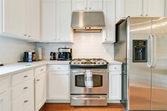 kitchen featuring wall chimney exhaust hood, appliances with stainless steel finishes, decorative backsplash, and white cabinets