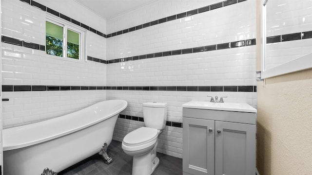 bathroom featuring toilet, tile walls, a tub to relax in, and vanity