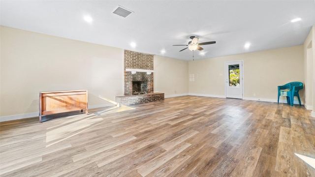 unfurnished living room featuring ceiling fan, light wood-type flooring, and a fireplace