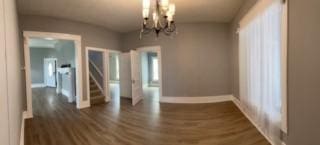 unfurnished dining area with a notable chandelier and dark hardwood / wood-style flooring