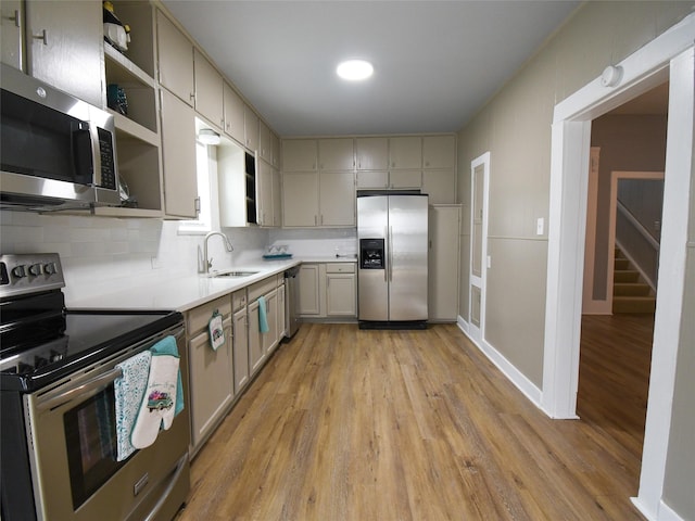 kitchen featuring gray cabinetry, sink, light hardwood / wood-style flooring, decorative backsplash, and appliances with stainless steel finishes