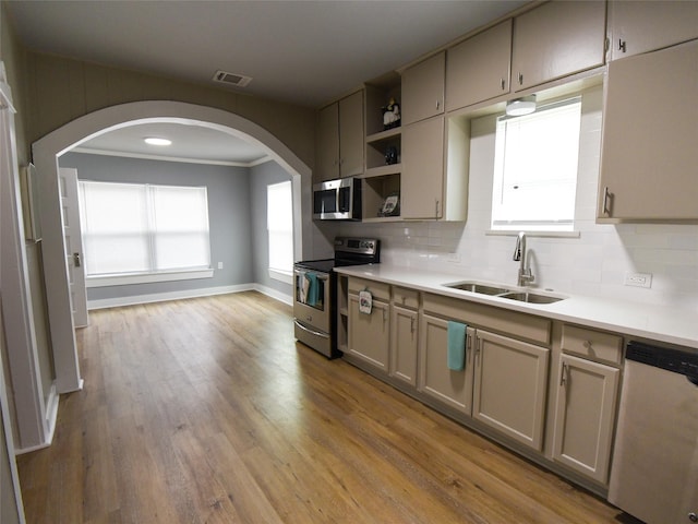 kitchen with backsplash, crown molding, sink, light hardwood / wood-style flooring, and stainless steel appliances