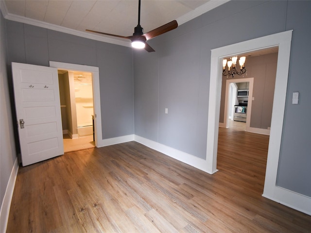 empty room with hardwood / wood-style floors, ceiling fan with notable chandelier, and ornamental molding