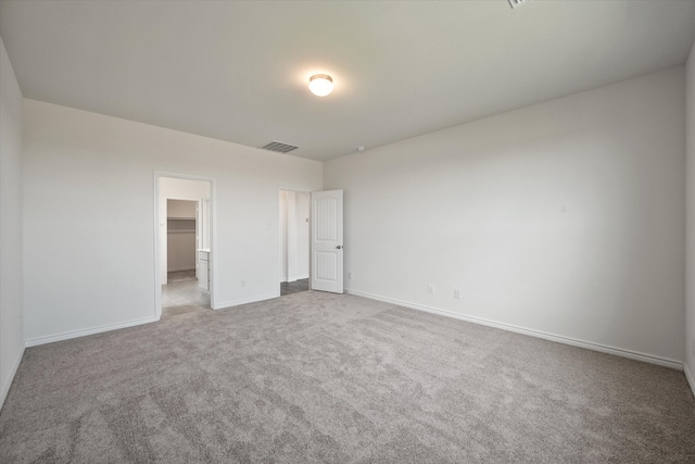 unfurnished bedroom featuring light carpet, a walk in closet, and a closet