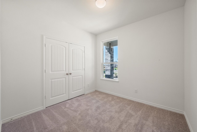 unfurnished bedroom featuring light carpet and a closet