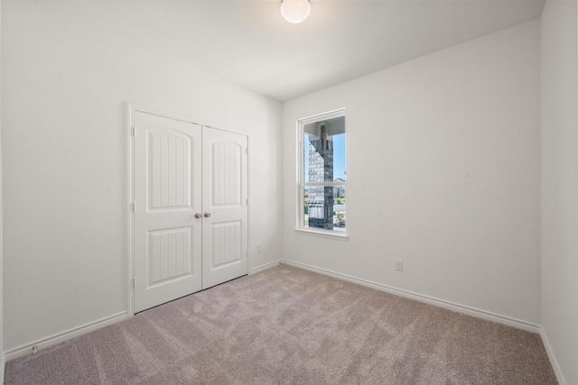 unfurnished bedroom with a closet, baseboards, and carpet flooring