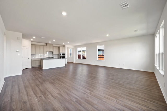 unfurnished living room featuring dark wood-type flooring and sink