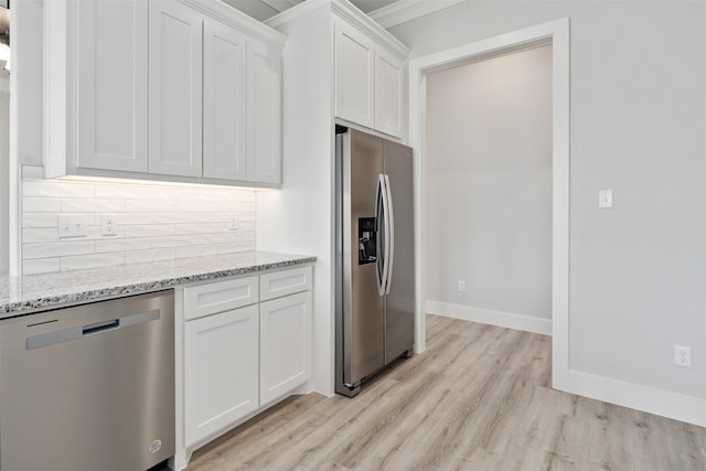 kitchen with light wood-type flooring, decorative backsplash, light stone countertops, white cabinets, and appliances with stainless steel finishes