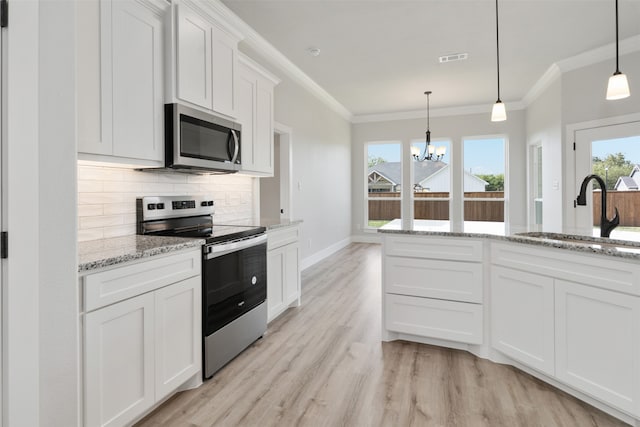 kitchen featuring white cabinets, appliances with stainless steel finishes, hanging light fixtures, and sink