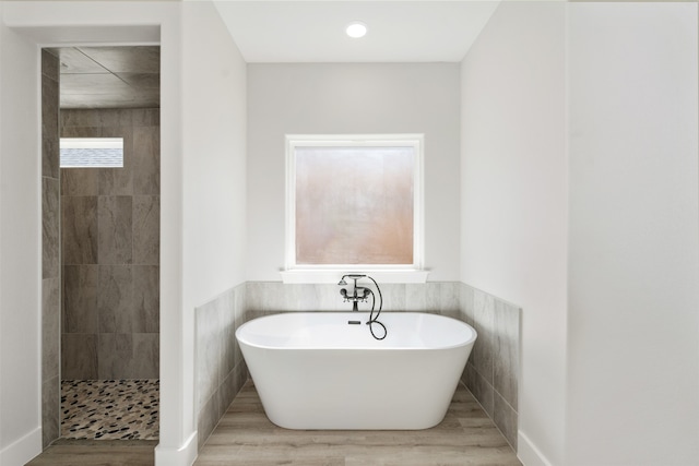 bathroom featuring tile walls, hardwood / wood-style floors, and independent shower and bath