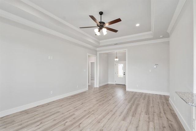 spare room featuring a raised ceiling, ornamental molding, light hardwood / wood-style flooring, and ceiling fan